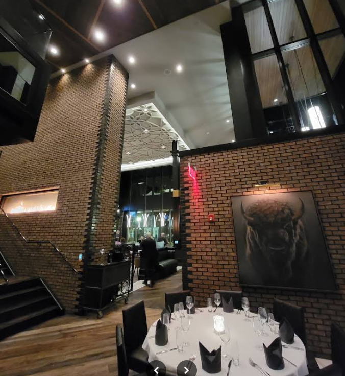 The two-story brick dining room at Anthony's Chophouse with the large bison portrait on the wall