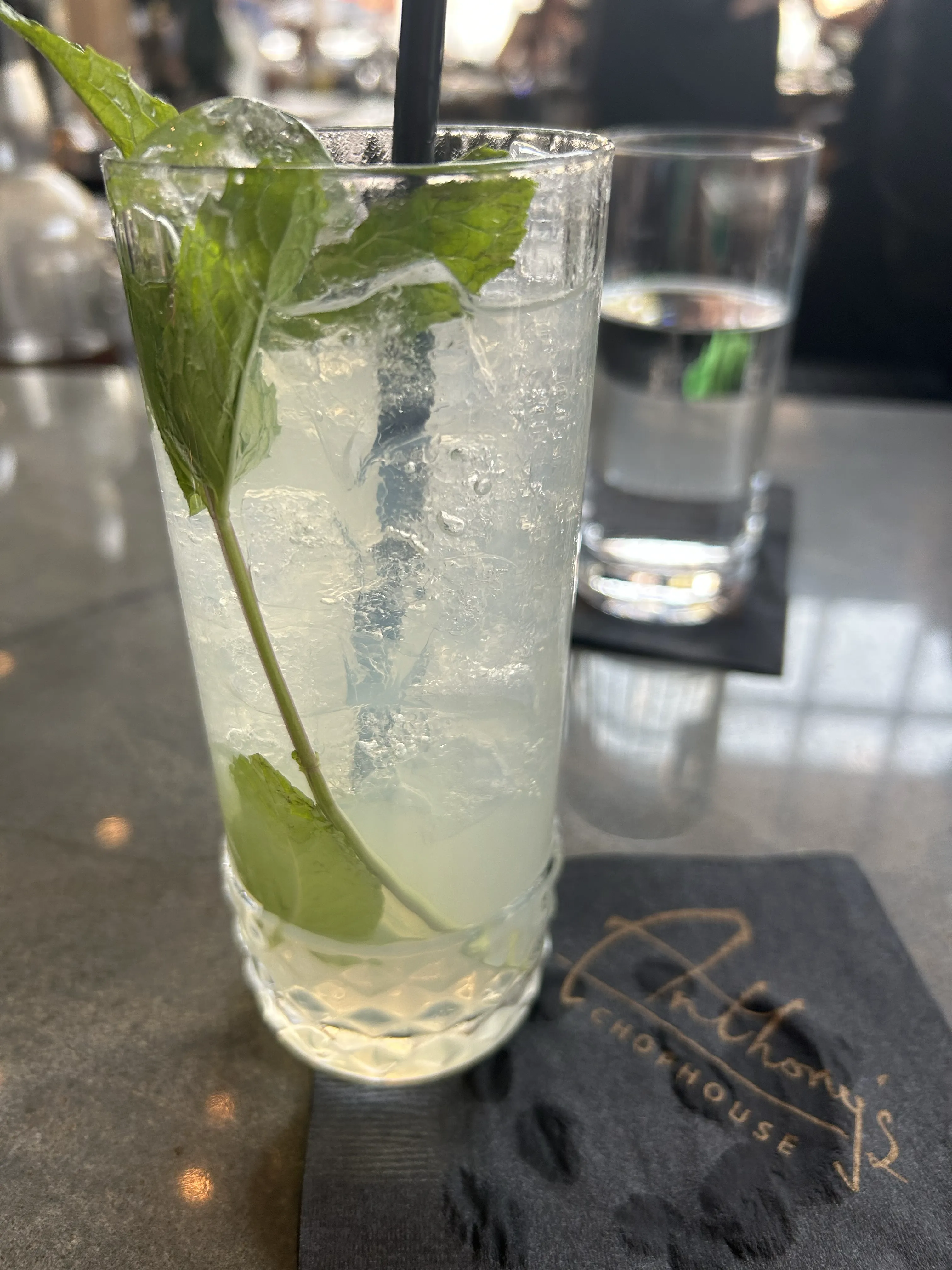 A tall mojito loaded with fresh mint on an Anthony's Chophouse coaster