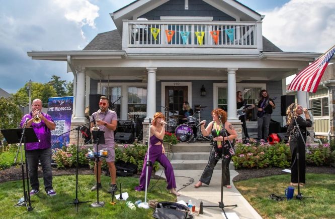 A band performing on a front porch at Carmel PorchFest with a crowd watching from the lawn