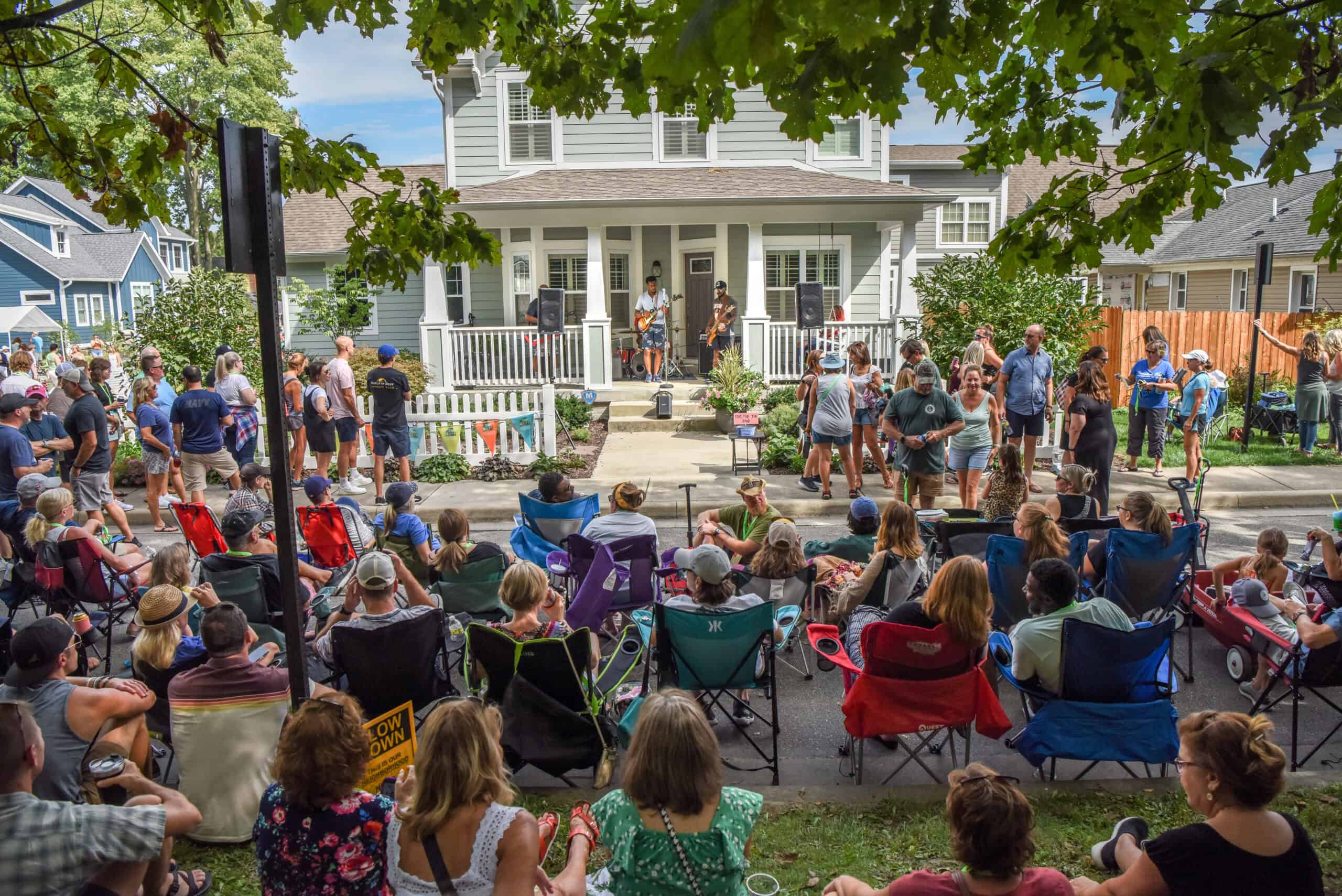 A band performing on a front porch with a crowd on the lawn at Carmel PorchFest