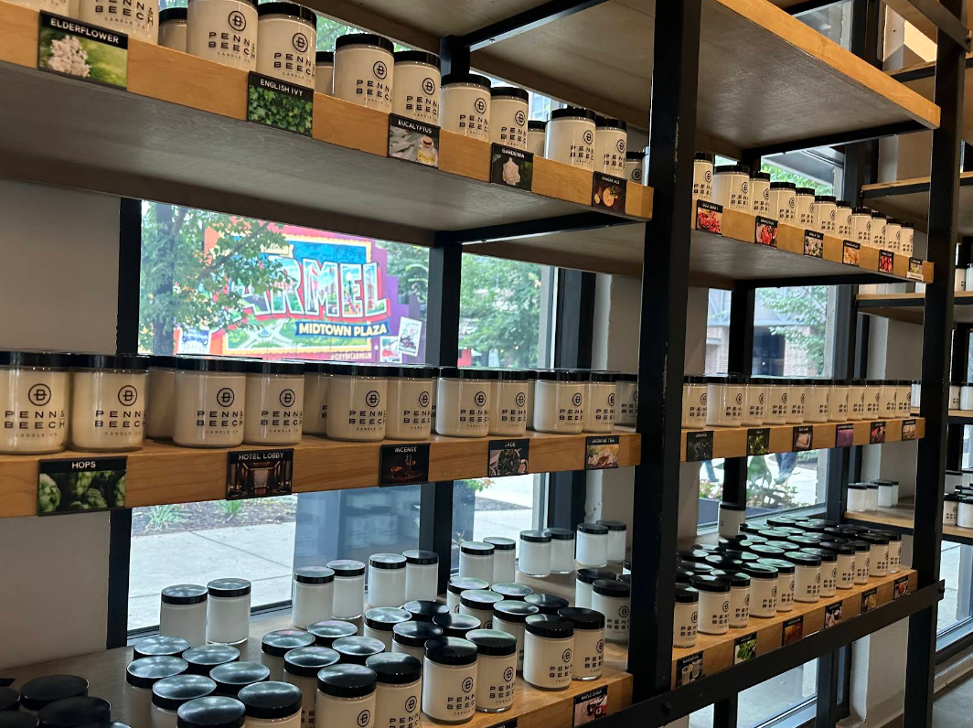 Shelves of Penn & Beech fragrance testers with the Midtown Plaza sign visible through the window